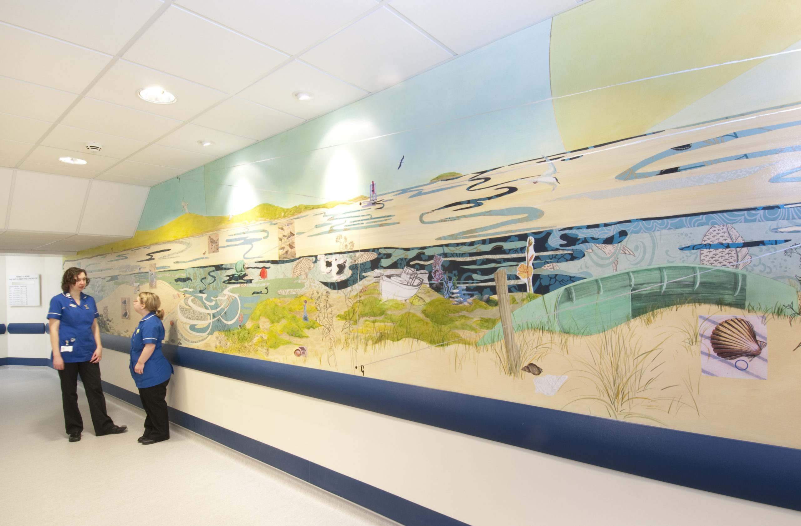 An NHS corridor in Musgrove Park Hospital with a large beach seaside wall print running across one side of the wall