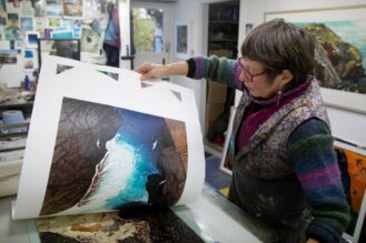 An image of Julie Manning in her studio looking through some prints