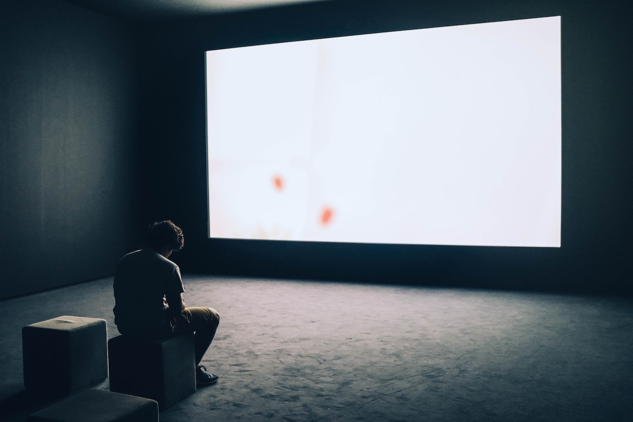 Man sitting in front of a large white screen.