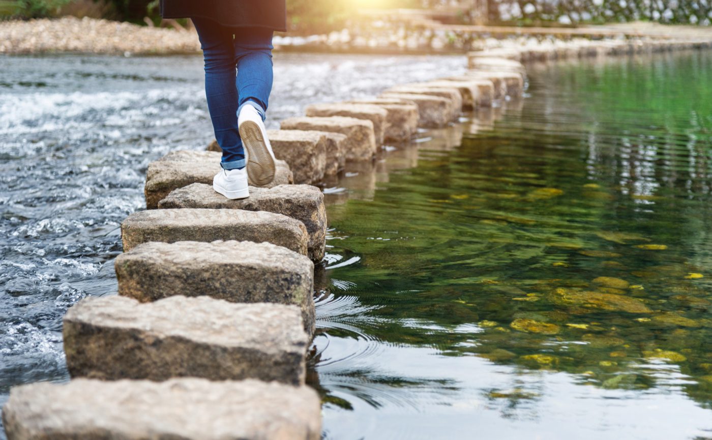 A person crossing some stepping stones over a river